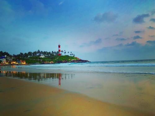 a lighthouse on an island in the ocean with a beach at The Ocean Park Beach Resort in Kovalam