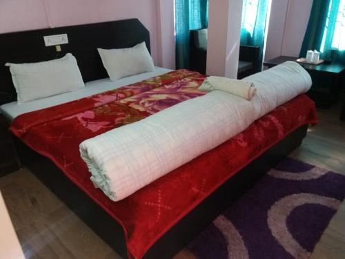 a large bed with a red blanket on it at Buddha Hotel in Tawang