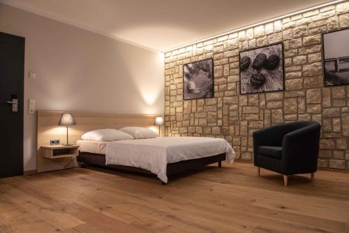 een slaapkamer met een bed en een stenen muur bij Wein Erlebnis Hotel Maimühle in Perl