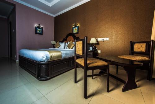 a bedroom with a bed and a table and a desk at Kallada Regency in Irinjālakuda