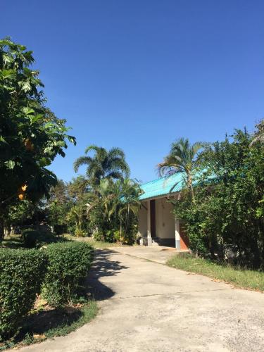 a building with palm trees and a road at First Garden Home Resort in Si Sa Ket