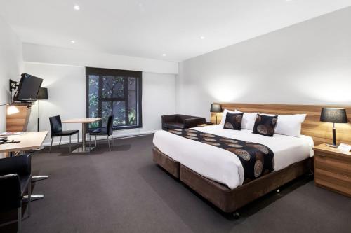 Best Western Plus Ballarat Suites في بالارات: غرفة نوم بسرير كبير وطاولة وكراسي
