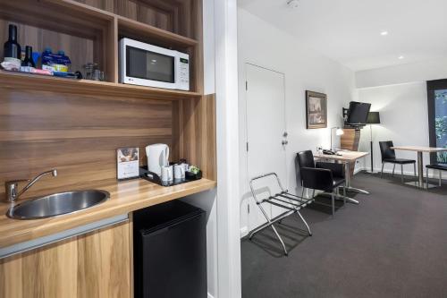 a kitchen with a sink and a table with chairs at Ballarat Suites in Ballarat