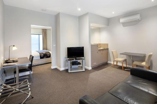 a living room with a couch and a television and a bed at Ballarat Suites in Ballarat