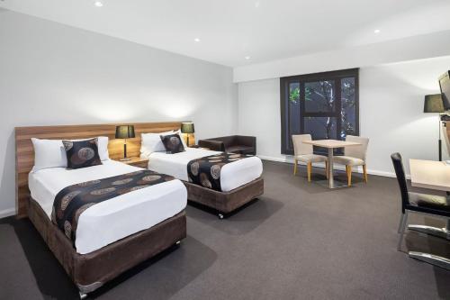 a hotel room with two beds and a table and chairs at Ballarat Suites in Ballarat