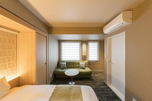 a bedroom with a bed and a green couch at Kyoto Gion U-BELL Hotel in Kyoto