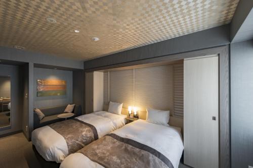 a hotel room with two beds and a chair at Kyoto Gion U-BELL Hotel in Kyoto