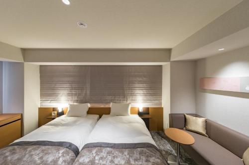 a bedroom with a large bed and a couch at Kyoto Gion U-BELL Hotel in Kyoto