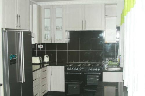 cocina con nevera negra y armarios blancos en Amazing Guest House en Harare