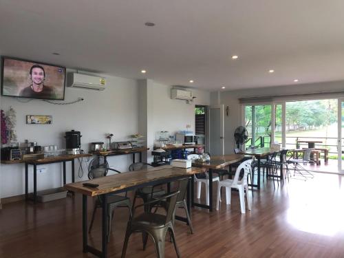 a room with wooden tables and chairs and a kitchen at The iKon Apartment in Ban Nong Pho