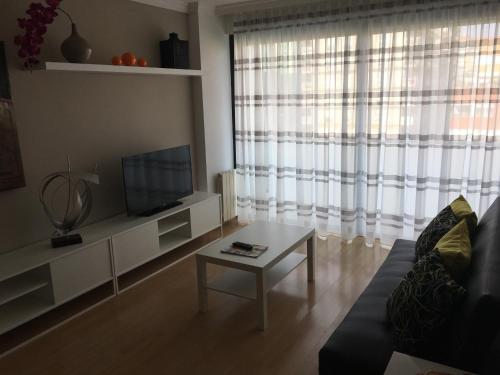 a living room with a couch and a tv and a table at Luxury apartment furnished and equipped in Terrassa