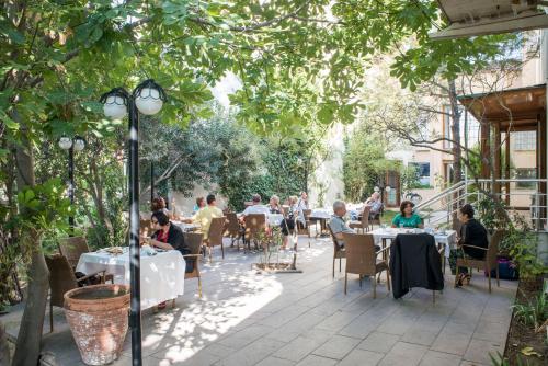 a group of people sitting at tables in a garden at Berksoy Hotel in Bergama