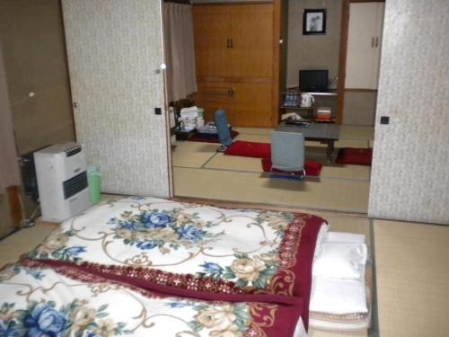 a room with a bed with a floral pattern on it at Mimatsuso Ryokan in Asahikawa