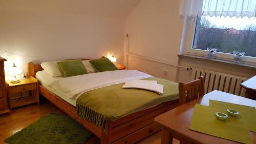 ブンツラウにあるEliza noclegiのベッドルーム1室(緑の枕とテーブル付)
