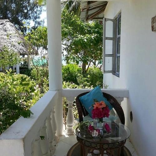 a balcony with a glass table with flowers on it at Driftwood Beach Lodge in Jambiani