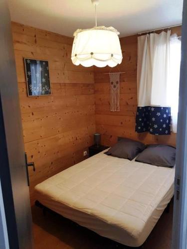 une chambre avec un lit et un lustre dans l'établissement Appartement Flocon, 2 chambres, à Saint-Sorlin-dʼArves
