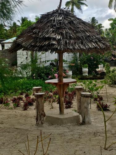 a table with a straw umbrella in the sand at Driftwood Beach Lodge in Jambiani