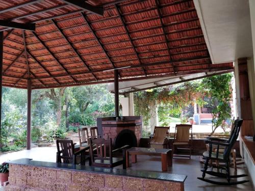 an outdoor patio with a fireplace and tables and chairs at Kabbe Holidays in Madikeri