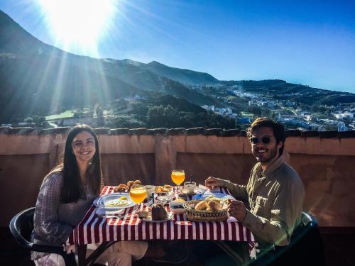 un uomo e una donna seduti a un tavolo con cibo e bevande di dar solaiman a Chefchaouen