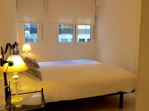 a bedroom with a white bed and two windows at Apartamento Oteiza in San Sebastián