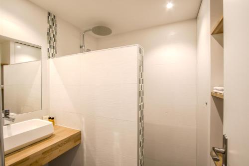 a white bathroom with a sink and a shower at Port de Caen Haut de Gamme in Caen