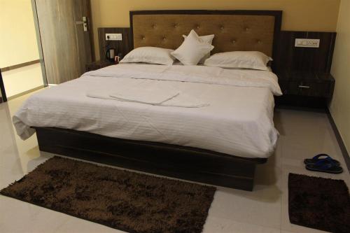 a bedroom with a large bed with white sheets and pillows at Hotel Shri Sharanam in Maheshwar