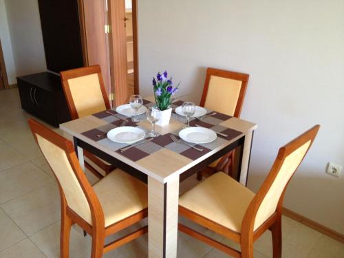 a dining room table with four chairs and a table with glasses at PSB Apartments in Midia Resort Aheloy in Aheloy