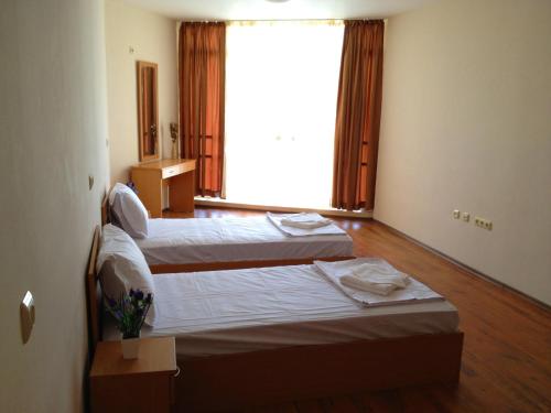 two beds in a room with a large window at PSB Apartments in Midia Resort Aheloy in Aheloy
