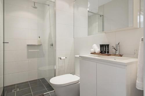 a white bathroom with a toilet and a shower at Lux 2BR Apt on Hindmarsh SQ-Pool-Gym-Sauna-Parking in Adelaide