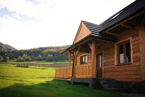 eine Holzhütte auf einem Feld neben einem Feld in der Unterkunft Noclegi Urbaniak in Tylmanowa