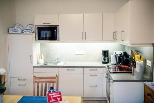 eine Küche mit weißen Schränken und einer Arbeitsplatte in der Unterkunft Bulemanns Haus in Husum