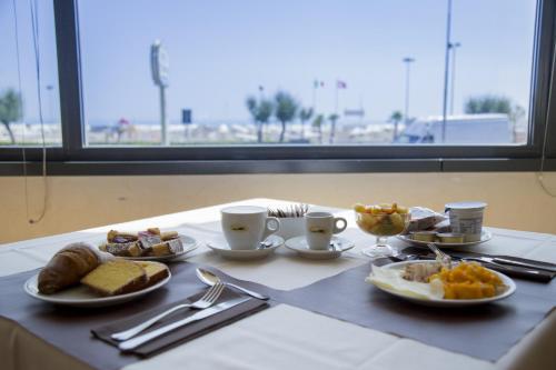 a table with plates of food on a table with a window at Hotel Metropole in Rimini