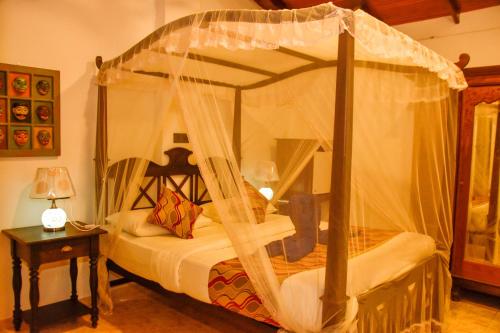 a bedroom with a canopy bed and a table with a lamp at Oriental Rest in Hikkaduwa