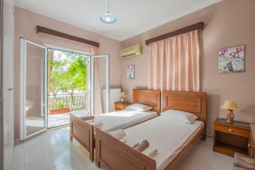 a bedroom with two beds and a large window at Dennis Tsilivi Houses & Studios in Tsilivi
