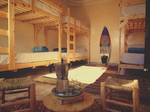 a room with two bunk beds and a table with chairs at Imsouane soul lodge in Imsouane