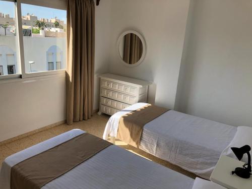 1 dormitorio con 2 camas y ventana en Apartamentos Alba en San Antonio Bay