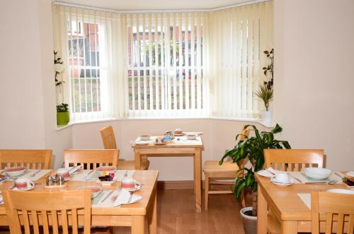 a dining room with wooden tables and chairs and windows at Pinewood House in Whitby