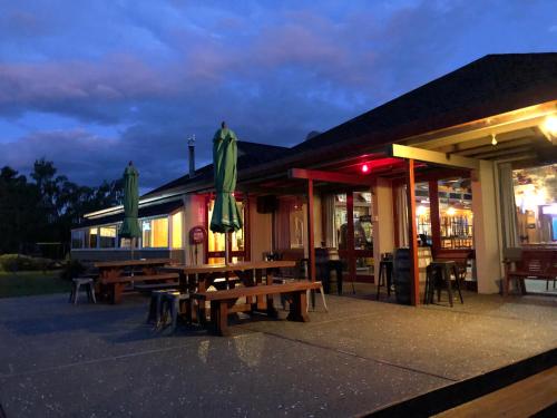 ein Restaurant mit Bänken und Sonnenschirmen vor einem Gebäude in der Unterkunft Te Anau Manapouri Lake Hotel in Manapouri