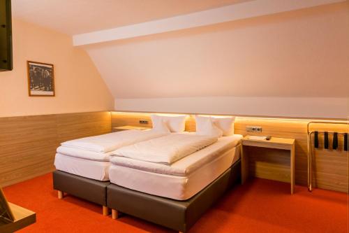 a bedroom with a bed with white sheets and pillows at CityHotel Kempten in Kempten