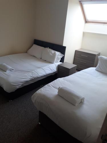 2 camas en una habitación con sábanas blancas y una ventana en Marvellous Meridian Maisonette en Ifield