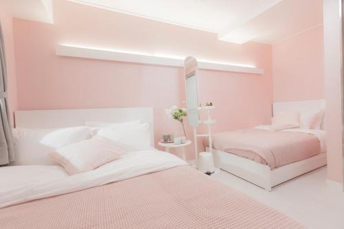 two beds in a white bedroom with pink walls at MJ Stay 2 in Seoul