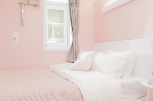 a white bed with white pillows and a window at MJ Stay 2 in Seoul