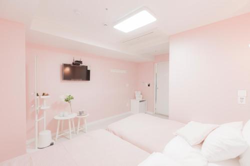 a white room with a bed and a tv on the wall at MJ Stay 2 in Seoul