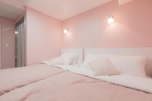 two beds in a room with white walls and lights at MJ Stay 2 in Seoul