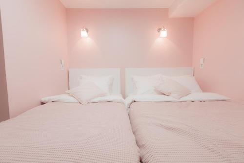 two beds in a room with white walls and lights at MJ Stay 2 in Seoul