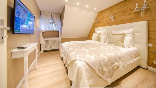 a bedroom with a white bed and a television at Luxuslodge Wernigerode in Wernigerode