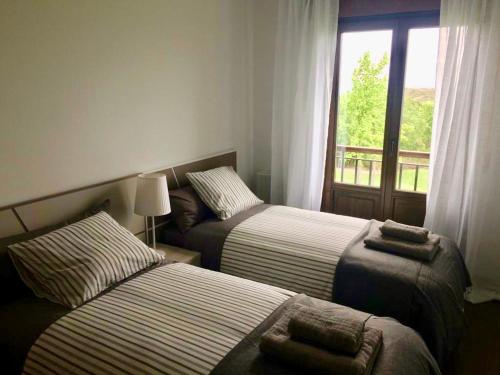 two beds in a hotel room with a window at Apartamentos Campo de Golf in Sojuela