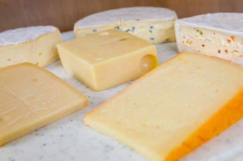 a group of different types of cheese on a counter at CityHotel Kempten in Kempten