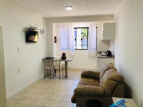 una sala de estar con un sofá y una mesa en Acácia Jurerê, en Florianópolis