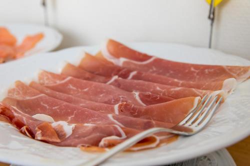 a plate with four pieces of bacon on a fork at CityHotel Kempten in Kempten